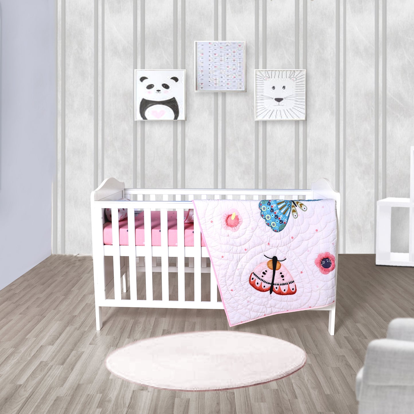 A baby crib set with a quilt featuring butterflies, placed in a nursery room with decorative wall art and a round white rug on the floor.