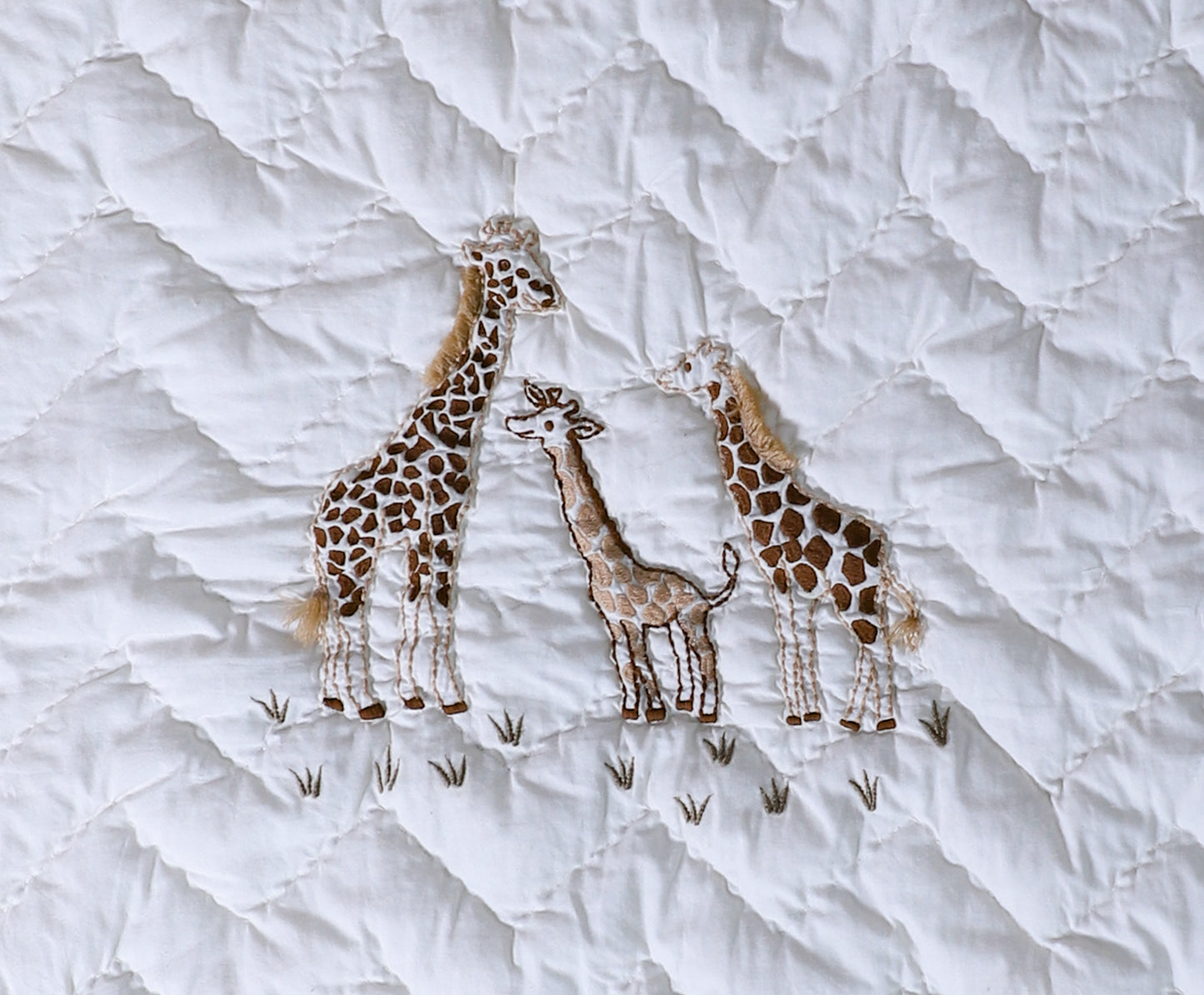Embroidered giraffes on a textured white fabric