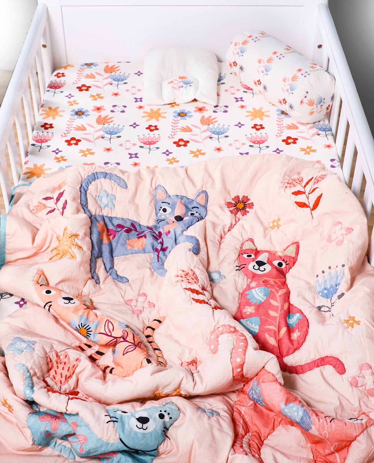 Crib with cat-themed bedding and plush toys