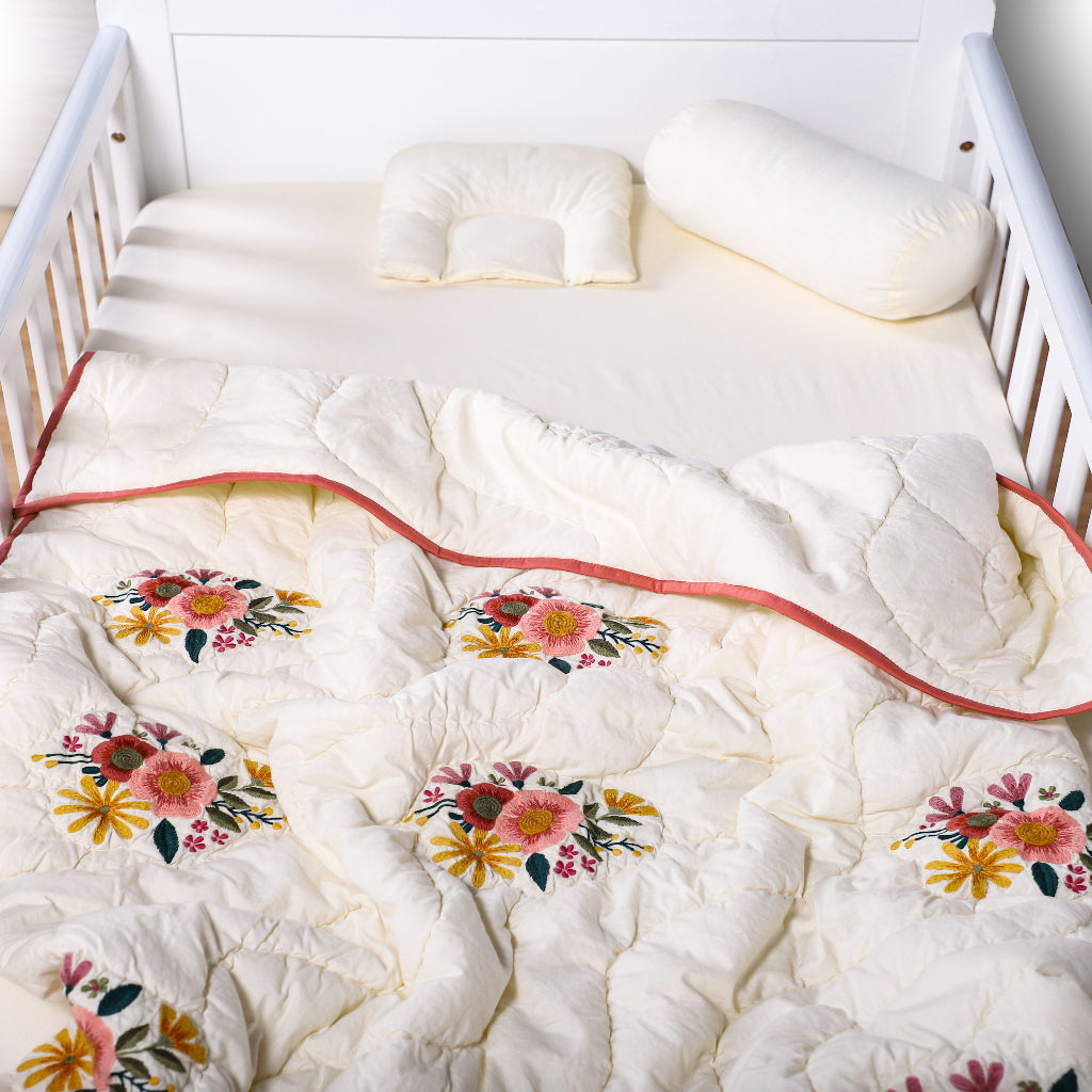 Floral-patterned quilt on a bed with white bedding and pillows.