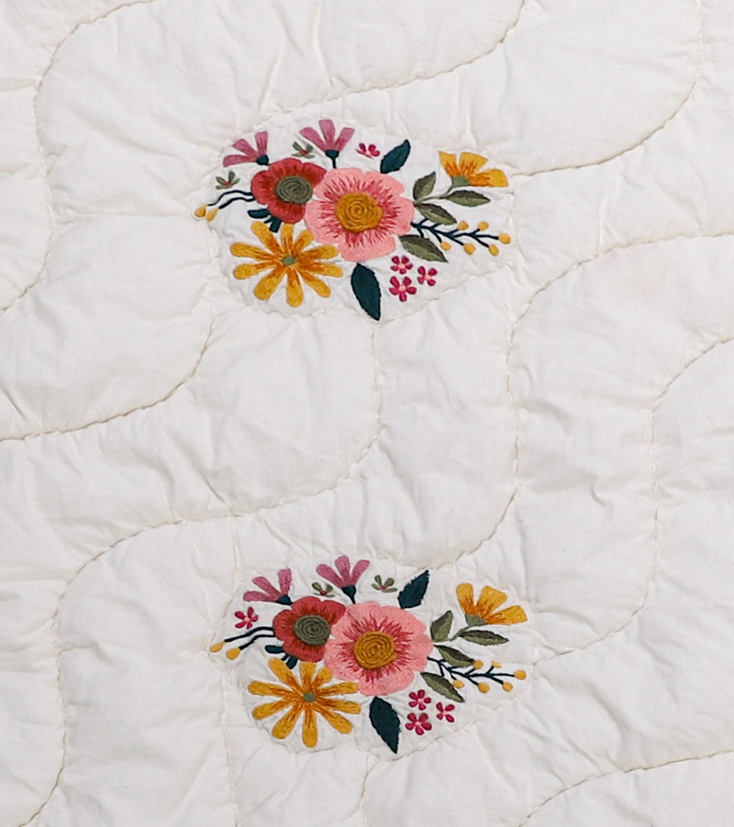 White quilt with floral embroidery patterns