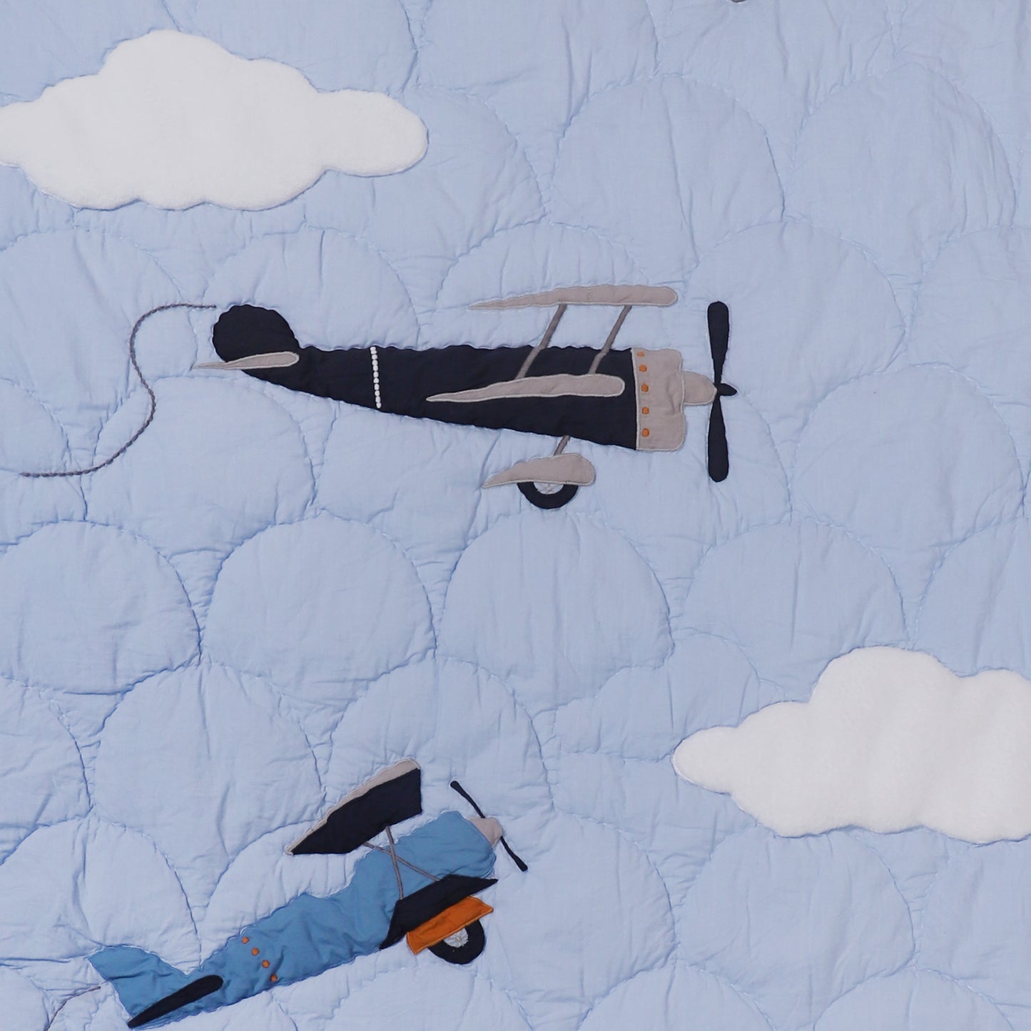 Quilt with airplane and skier design against a blue sky with clouds