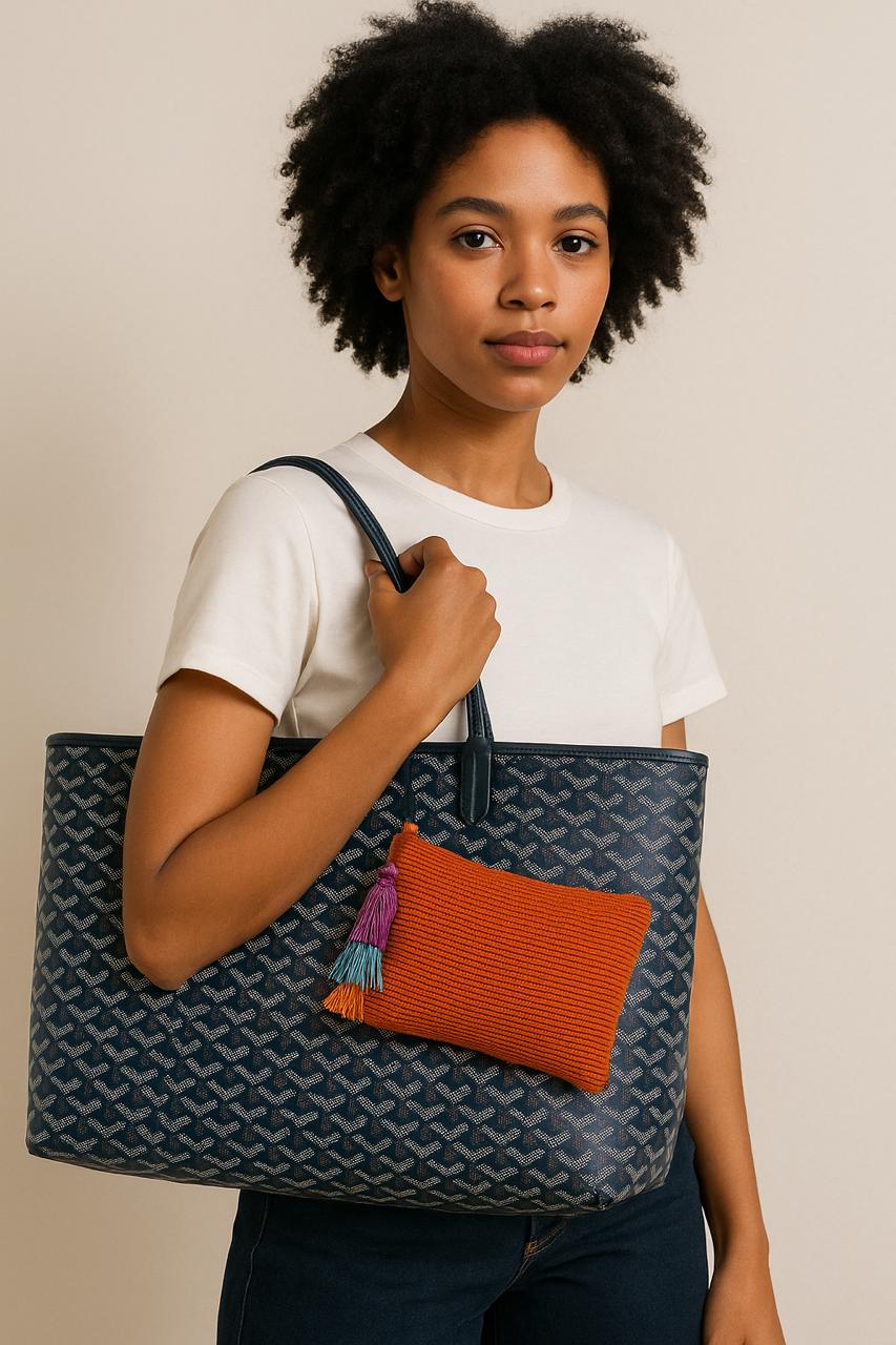 Person holding a large tote bag with an orange pouch on a beige background