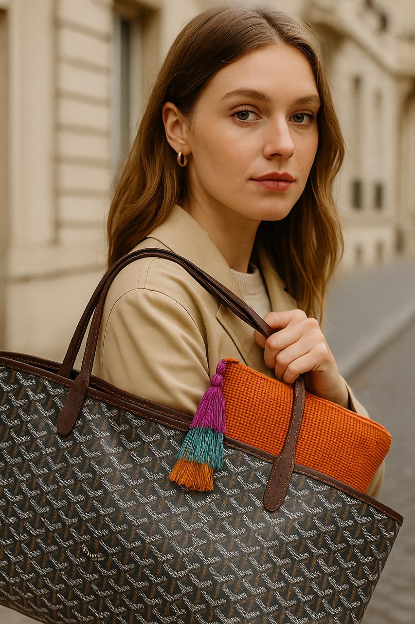 Woman holding a patterned handbag with colorful tassels outdoors.