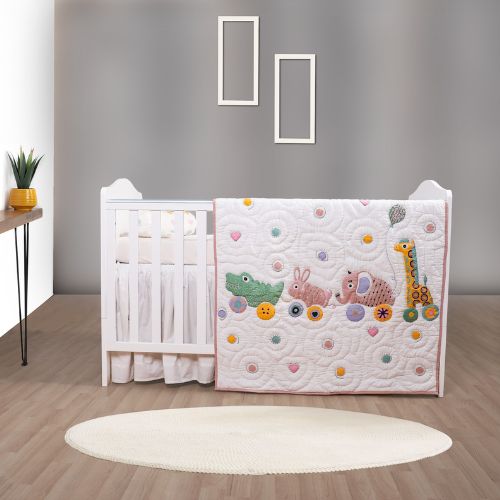 A baby quilt with animal patterns displayed on a crib in a nursery room.
