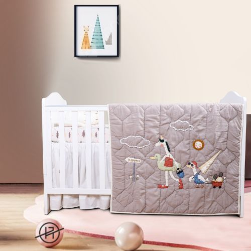 A baby quilt with duck designs displayed on a crib in a nursery room.