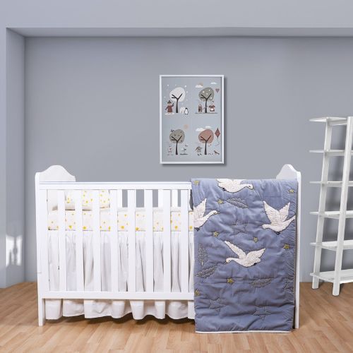 A baby quilt with a bird pattern displayed on a crib in a nursery room.