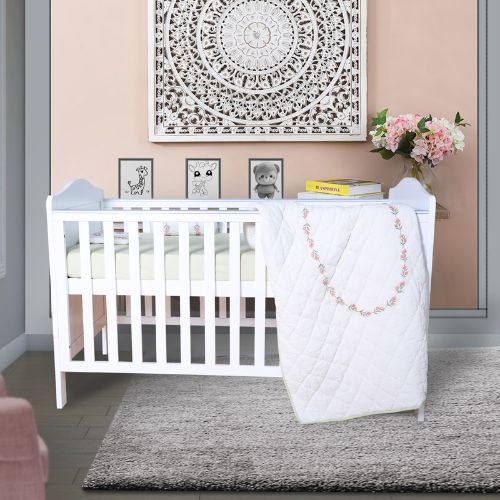A baby quilt with a floral stripe design displayed on a white crib in a nursery room.