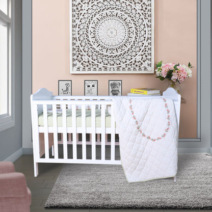 Nursery room with a white crib, pink chair, and decorative elements.