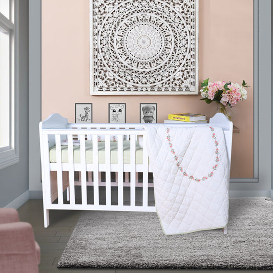Nursery room with a white crib, pink chair, and decorative elements.