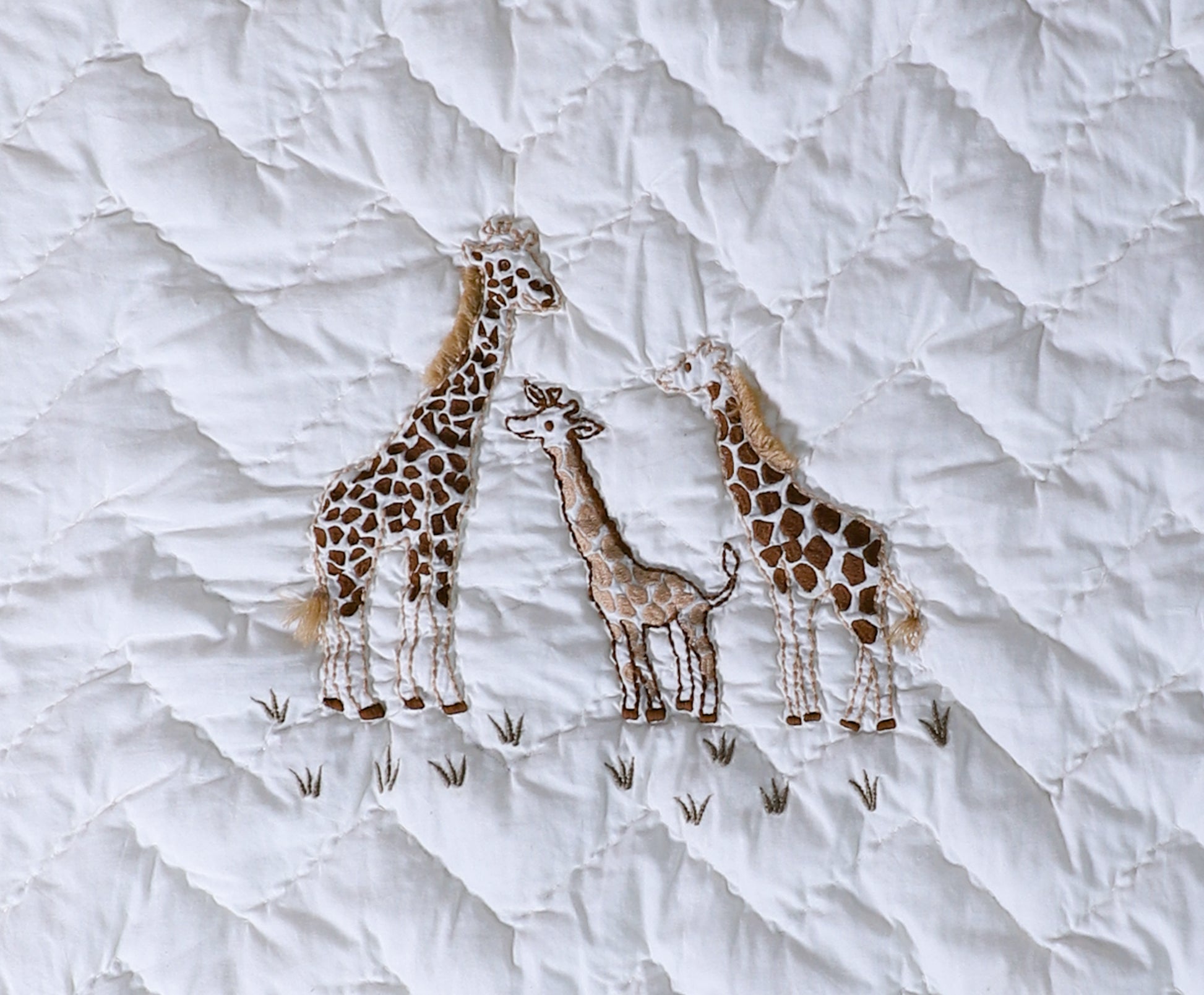 Embroidered giraffes on a textured white fabric