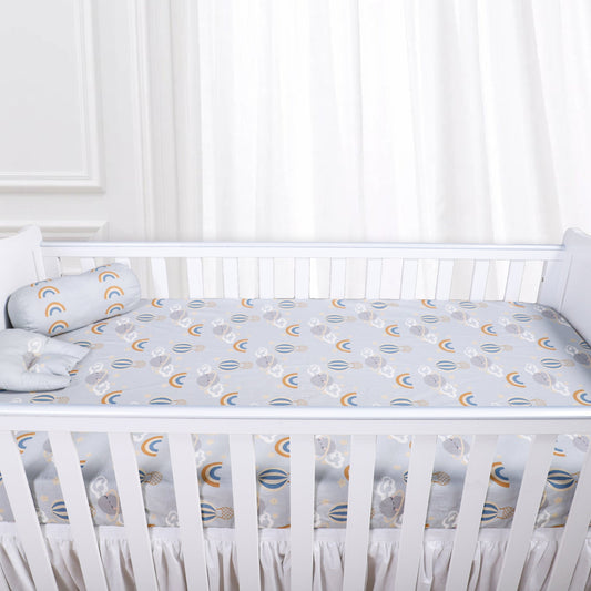 White crib with a fitted sheet featuring moon and star patterns in a nursery setting.