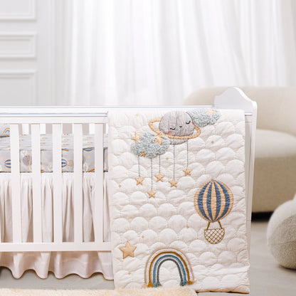 A baby crib set with a quilt featuring rainbow and whimsical animal character designs, along with a fitted sheet and a baby pillow.