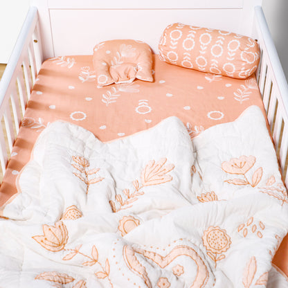 Crib with floral bedding and pillows in a soft peach color scheme.