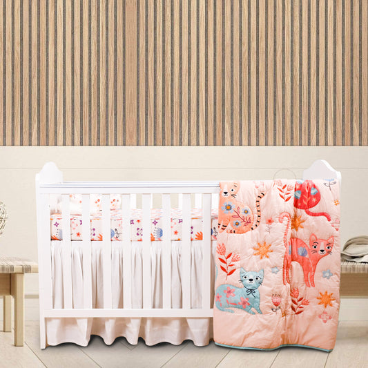A baby crib set with a quilt featuring cartoon cats, a fitted sheet, and a baby pillow, placed in a nursery room.