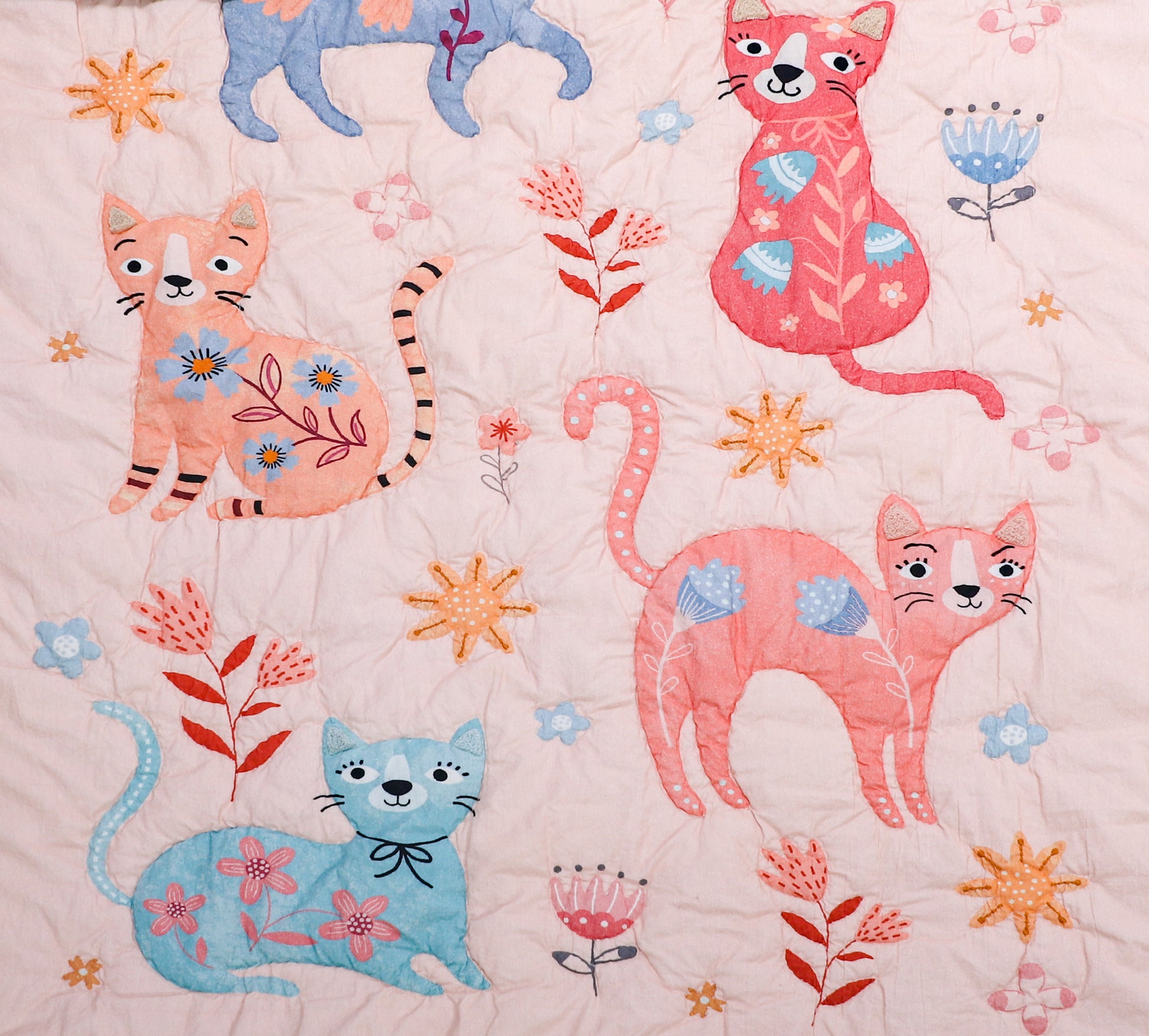 Quilt with colorful cats and floral patterns on a pink background
