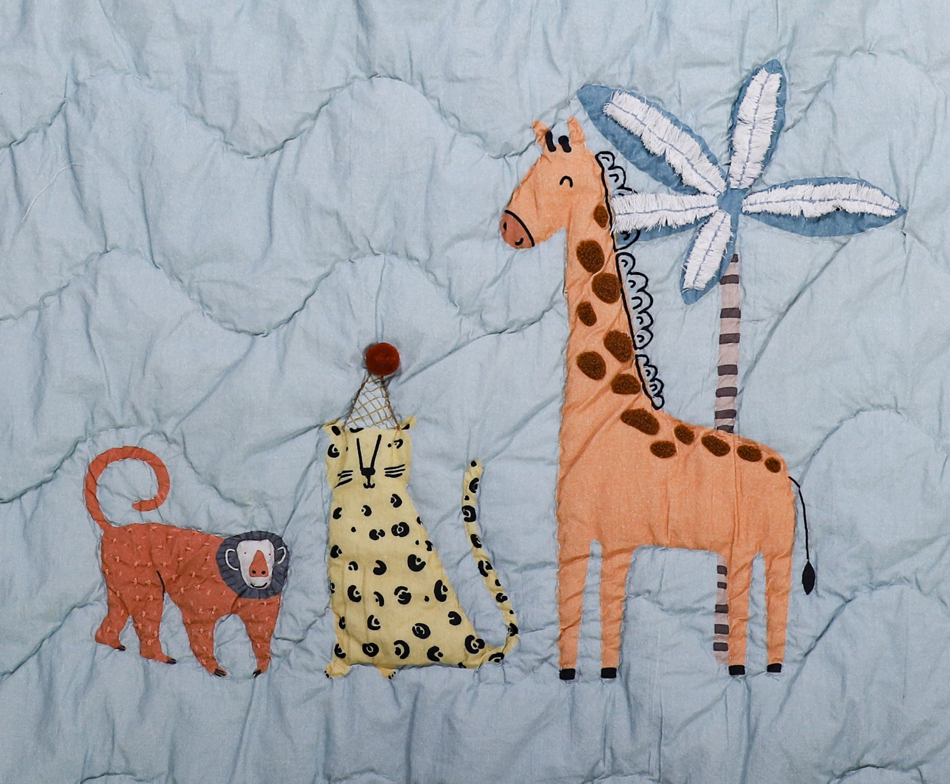 Quilt with appliqué of a lion, cheetah, and giraffe on a blue background