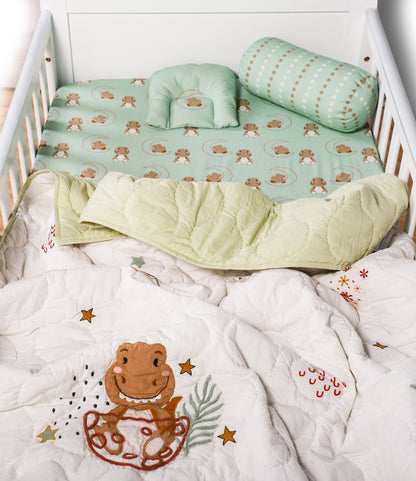 Crib with green bedding and frog-themed quilt