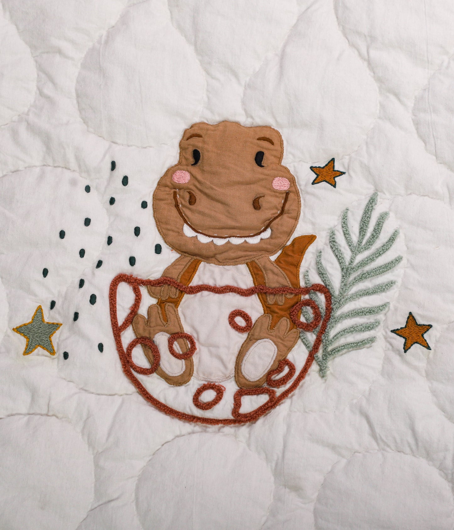Embroidered design of a monkey in a diaper on a quilt with stars and leaves.