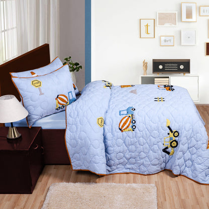 Light blue quilt with cartoon designs on a bed in a room with furniture and decor.