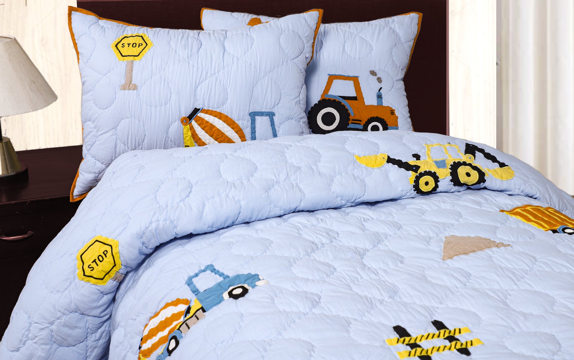 Children's bedding set with construction vehicle patterns on a bed.