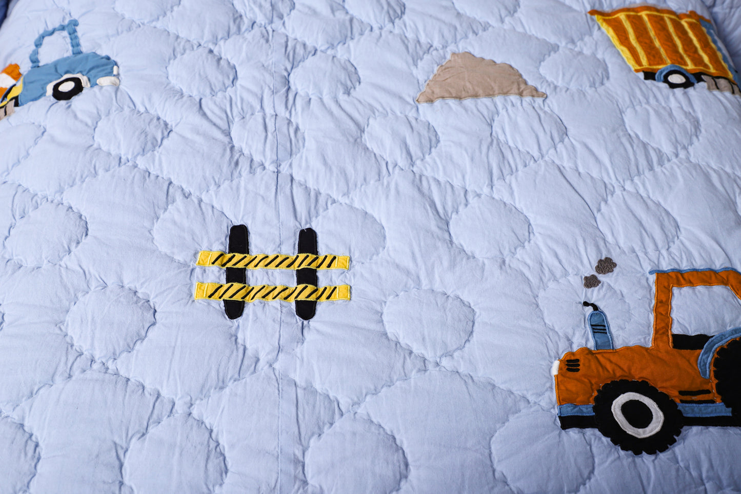 Children's quilt with construction vehicle pattern on a blue background