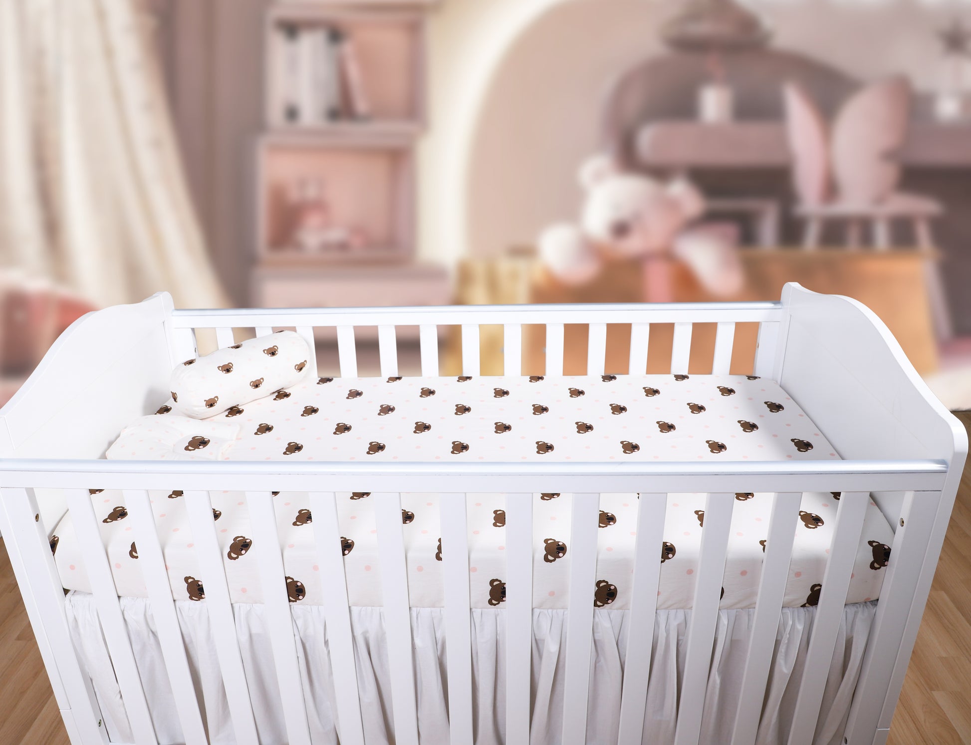White crib with a patterned mattress in a blurred nursery setting