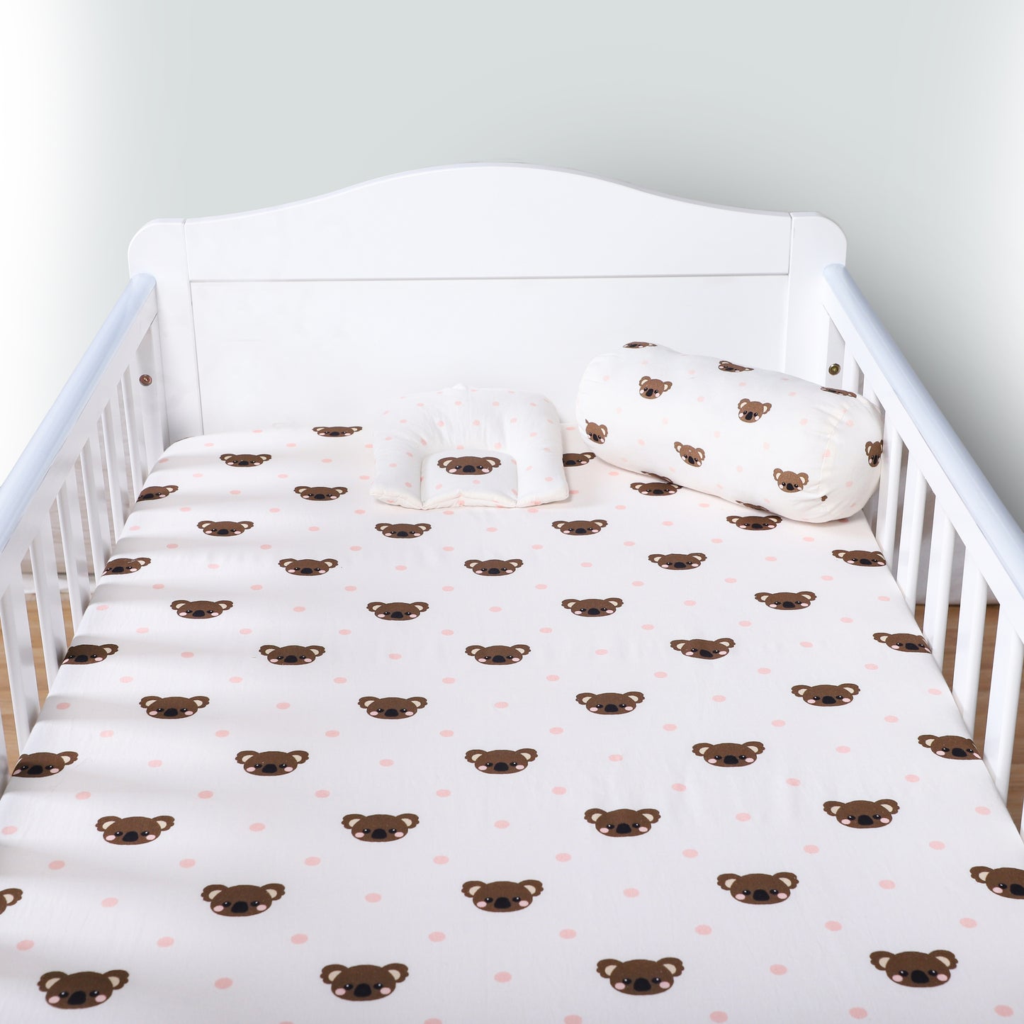 Crib with white sheet featuring brown bear patterns and matching pillow