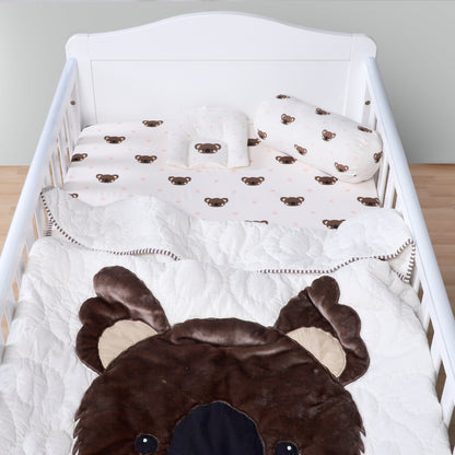 Baby crib with brown bear-themed bedding and pillows.