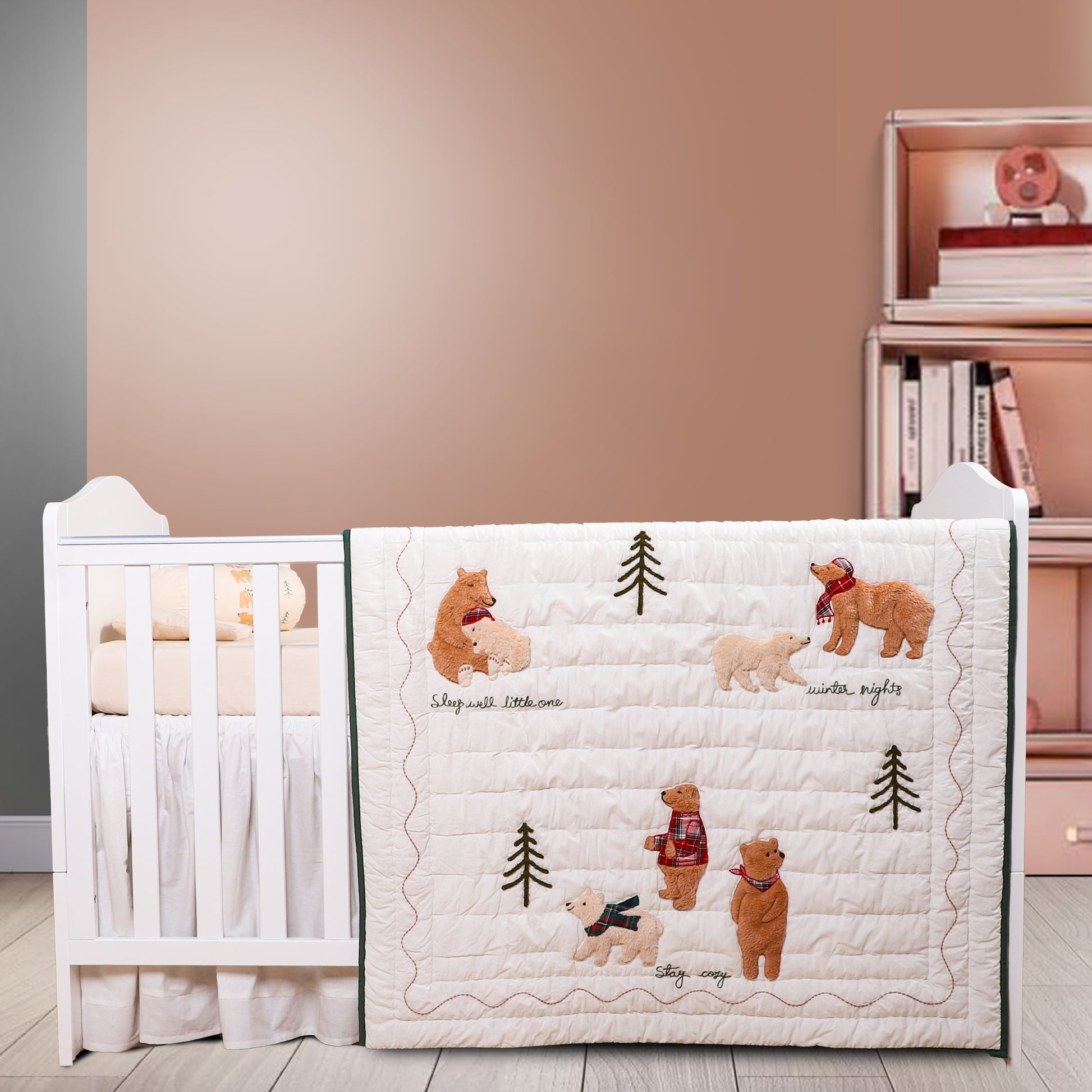 Baby crib with a quilt featuring bear illustrations in a room setting.