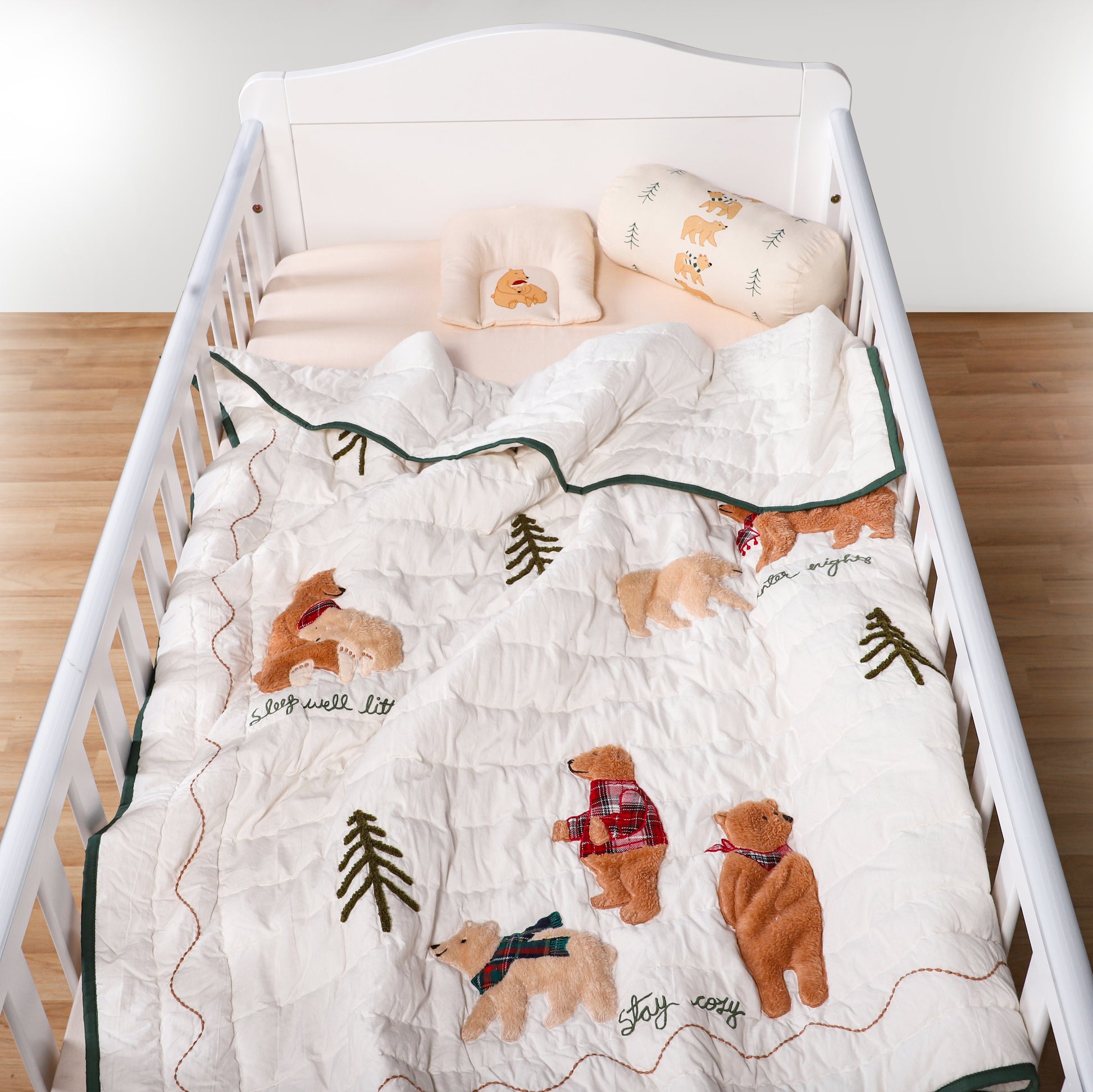 Crib with a white crib sheet featuring bear illustrations and text.