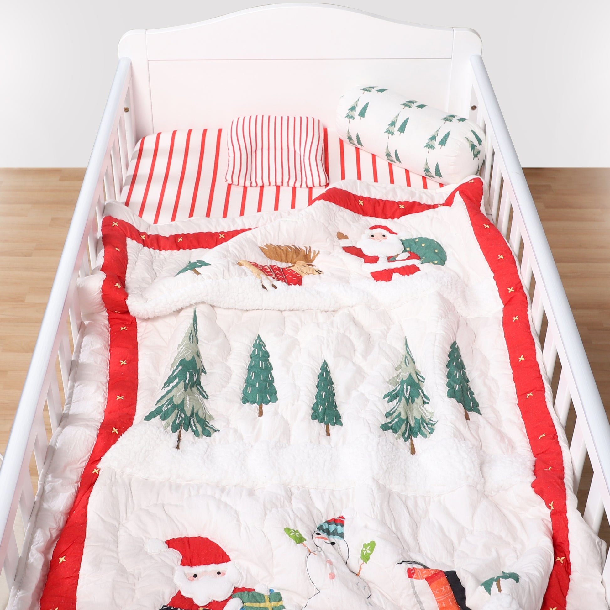 Christmas-themed crib set with Santa Claus and trees on a white crib.