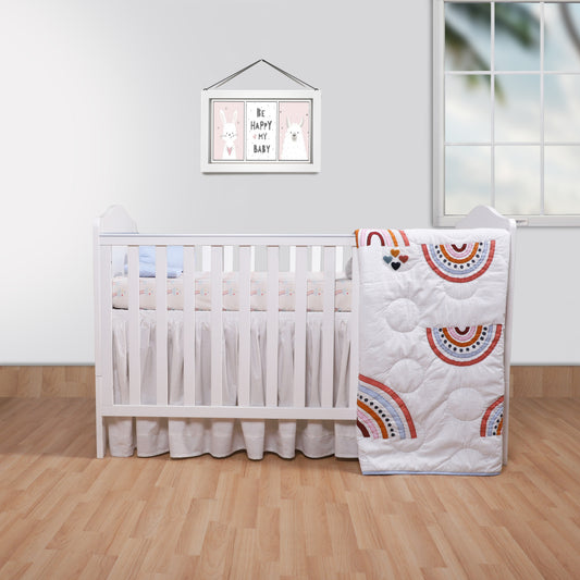 Nursery room with a crib and rainbow-patterned quilt on a wooden floor.
