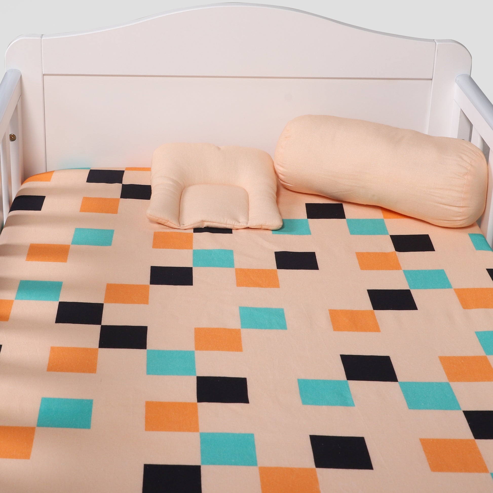 Bed with geometric patterned bedspread and two pillows on a white background