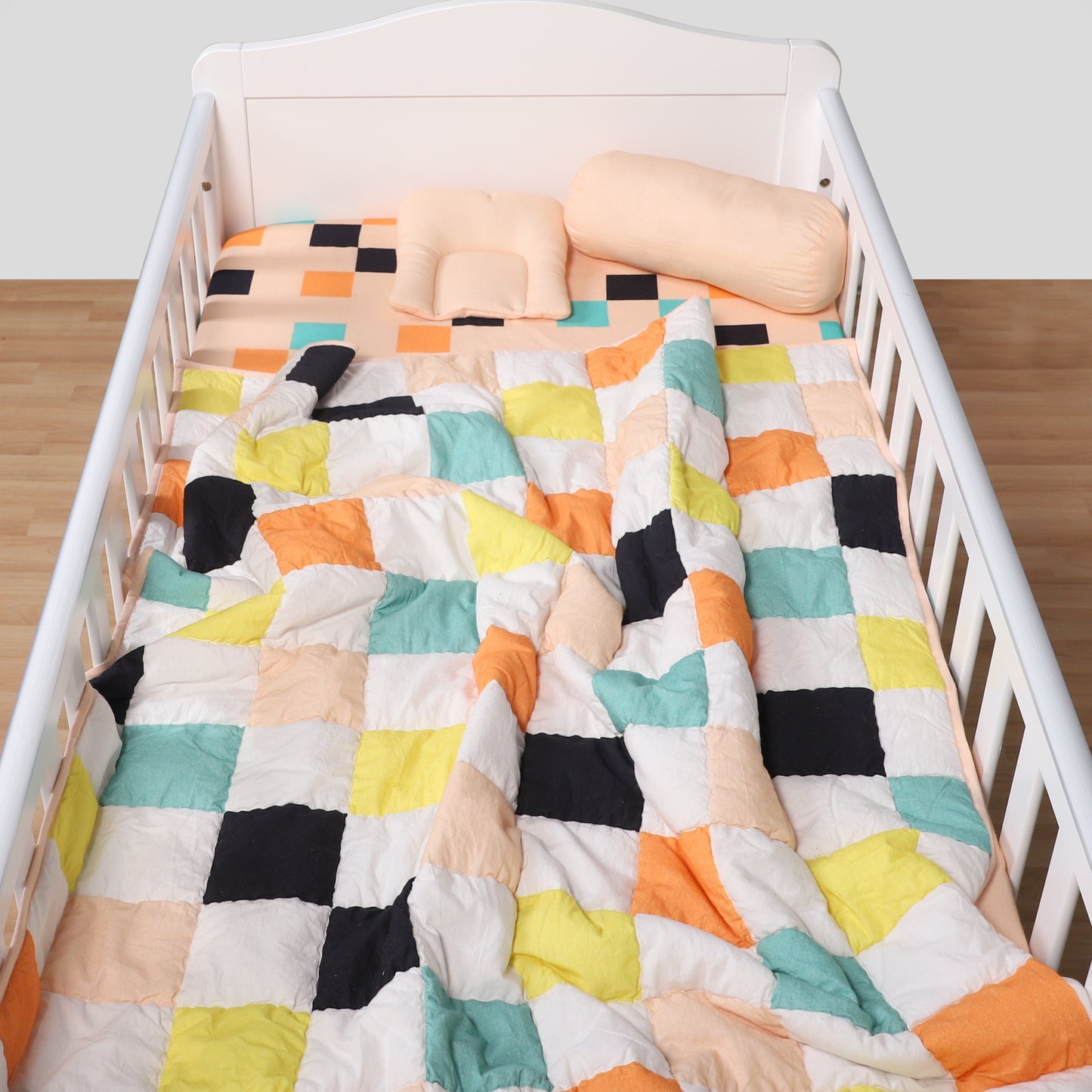 Colorful geometric quilt on a crib with a white background