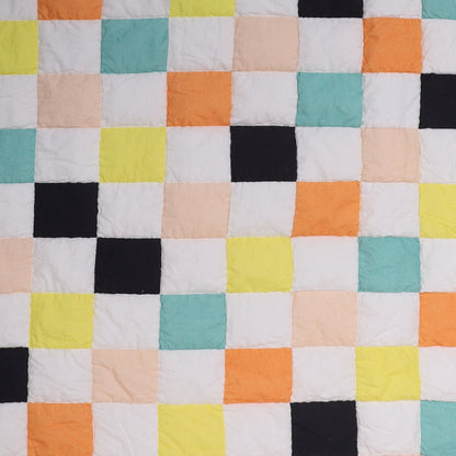 Colorful checkered quilt with various squares in different colors on a white background