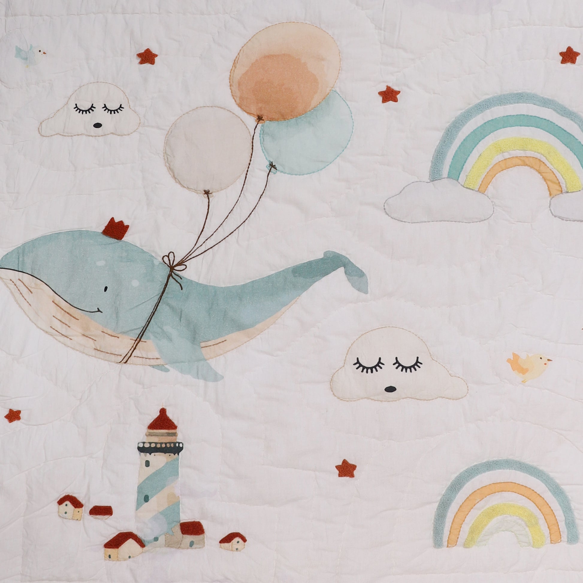 Children's quilt with whale, balloons, clouds, and rainbows on a light background
