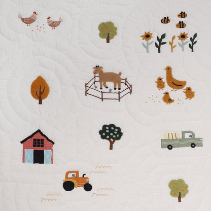 Children's quilt with farm-themed illustrations including animals, trees, and a truck on a light background.