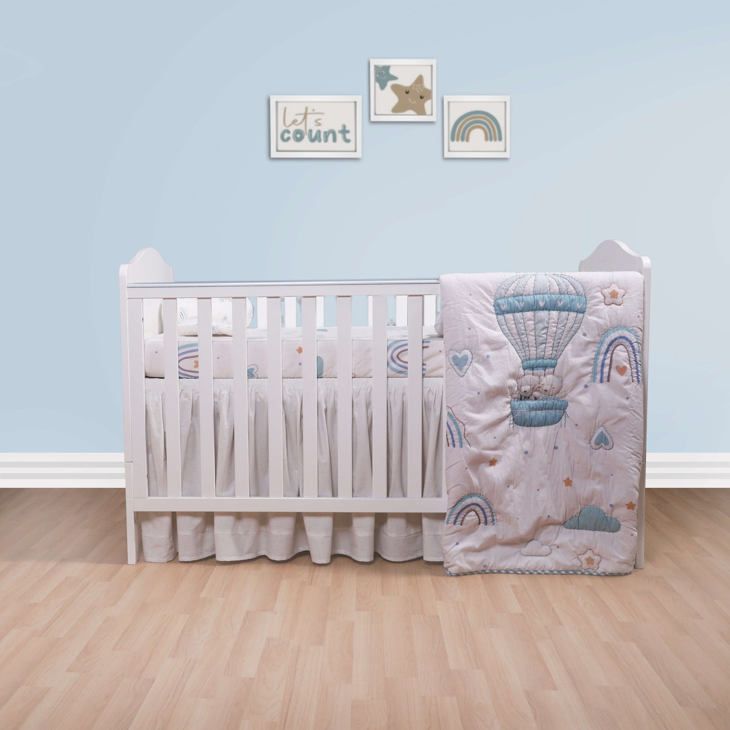 A baby quilt with hot air balloon design displayed next to a crib in a nursery room.