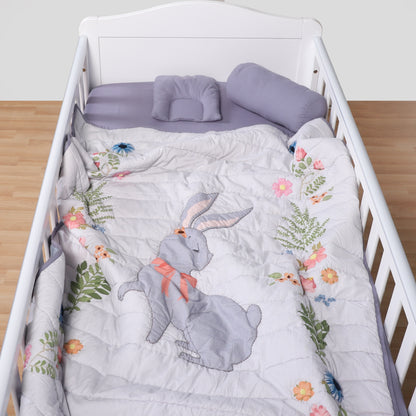 Crib with floral and rabbit-themed bedding on a wooden floor.