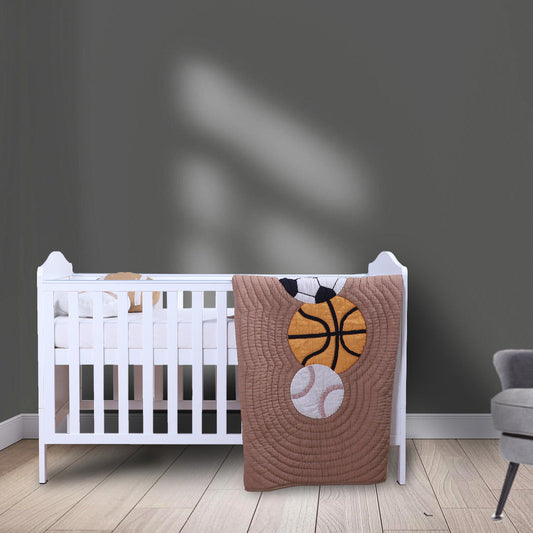 Nursery room with a crib and a brown blanket featuring sports balls on a gray wall.