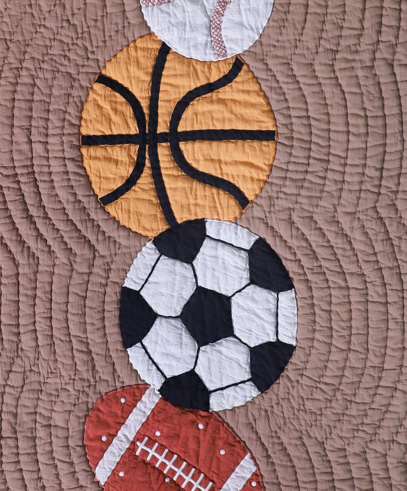 Quilt with sports-themed appliqué including a basketball, soccer ball, and football on a brown fabric background.