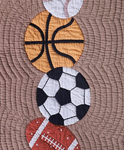 Quilt with sports-themed appliqué including a basketball, soccer ball, and football on a brown fabric background.