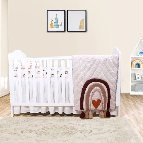 A baby quilt with a rainbow and heart design in a nursery room.