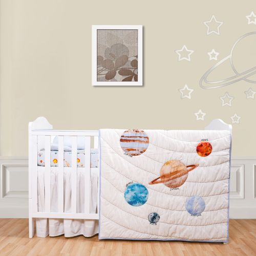 A baby quilt with a space theme, displaying various planets, laid out next to a crib and baby furniture, against a wall with star decorations.