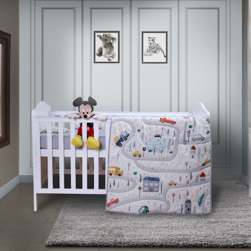 A baby quilt with a road and cars design, displayed in a nursery room.