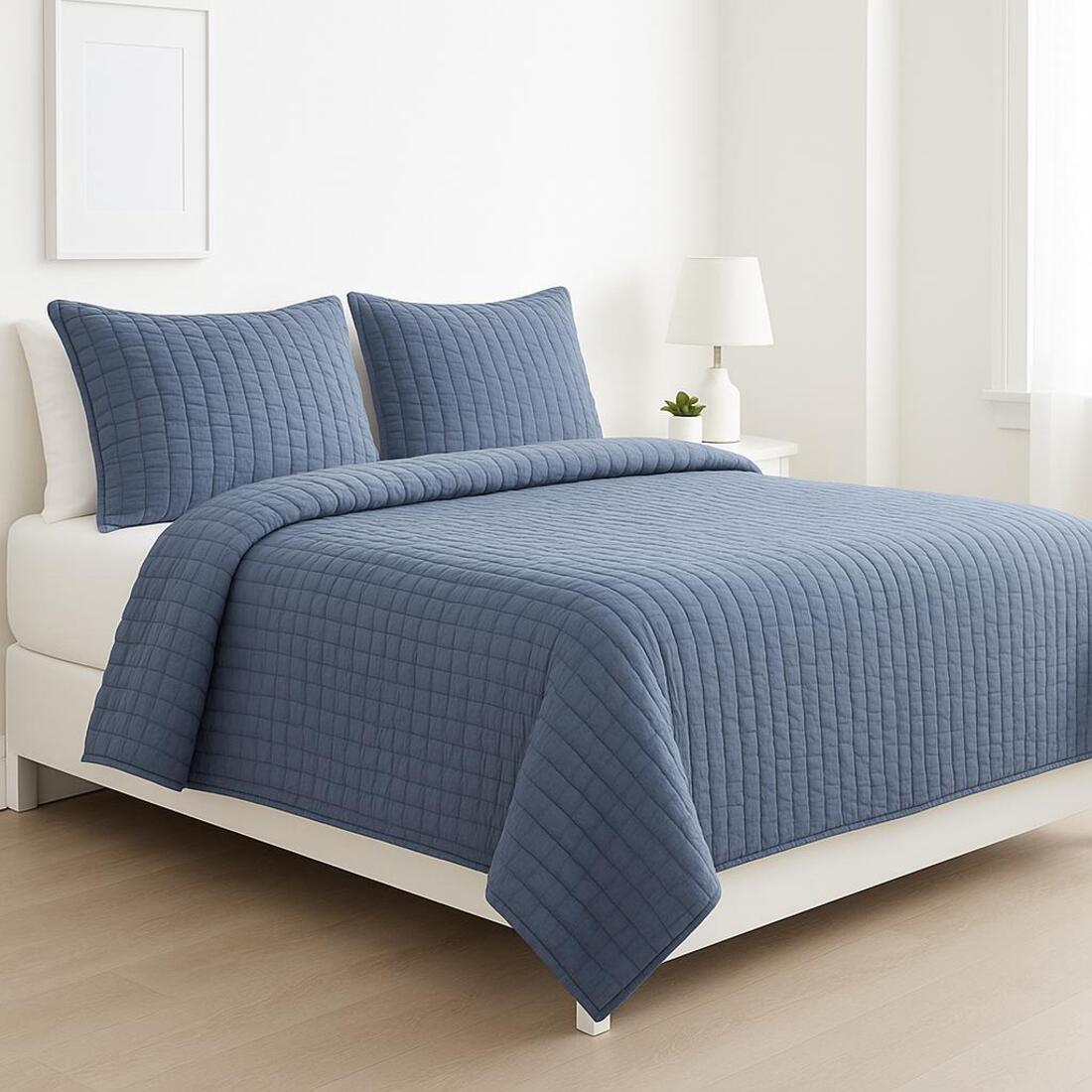 Blue quilted coverlet set on a bed in a bedroom setting