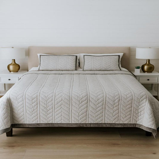 Neatly made bed with a quilt and pillows in a bedroom setting.