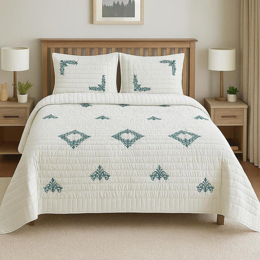 White quilt with green patterns on a bed in a bedroom setting