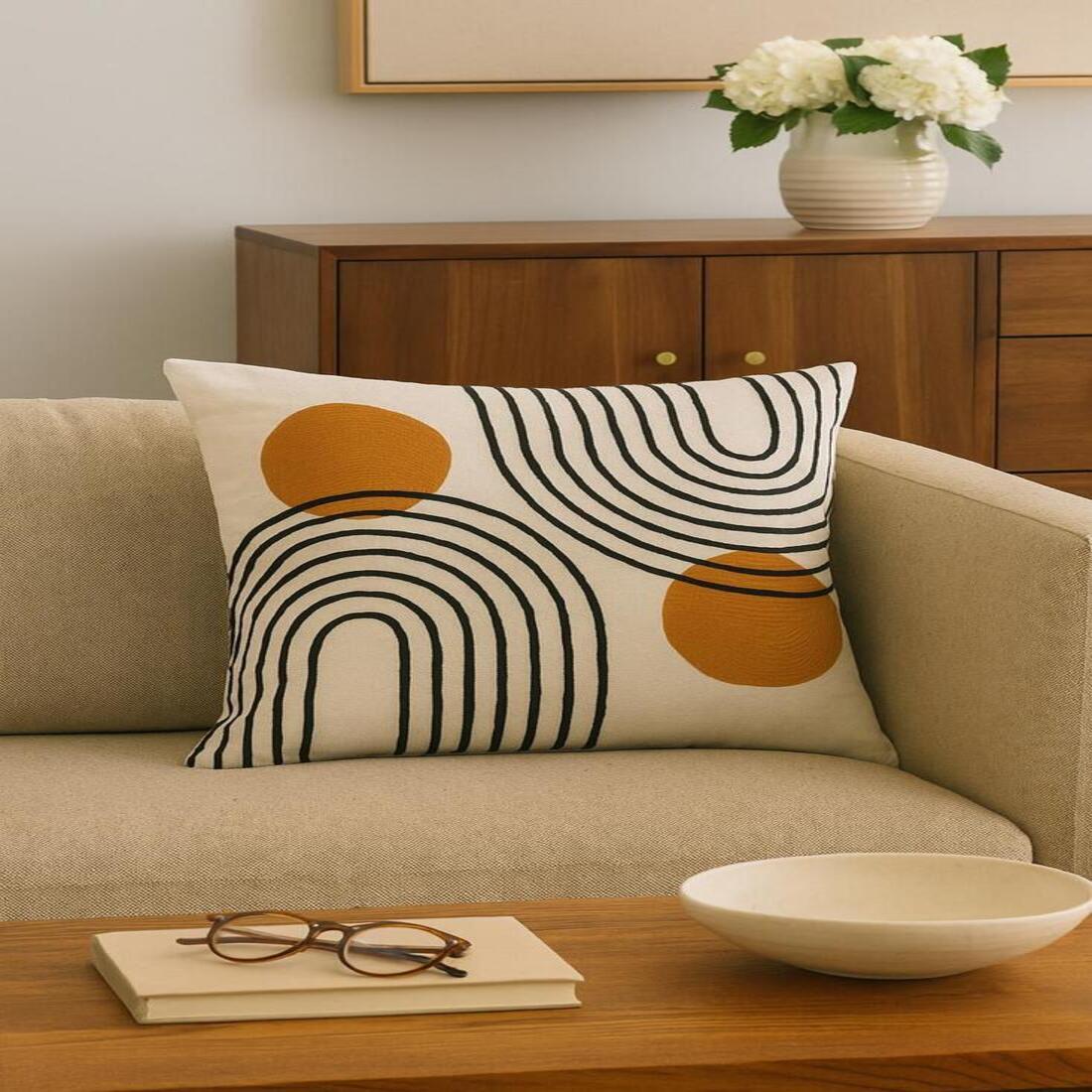 Decorative pillow with geometric pattern on a beige sofa in a living room setting.